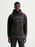 Alpinestars Sweat à capuche Infinite Washed Oversize, sweat à capuche sportswear décontracté, noir délavé, polaire avec finition effet neige, poche kangourou et texte du logo Alpinestars brodé en blanc, vue de face sur modèle