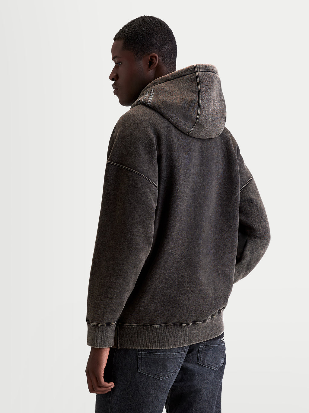 Alpinestars Sweat à capuche Infinite Washed Oversize, vêtement sportswear pour homme, noir délavé avec finition effet neige, polaire de coton, coupe décontractée, vue de dos sur modèle mettant en valeur le logo brodé sur la capuche et les détails côtelés.