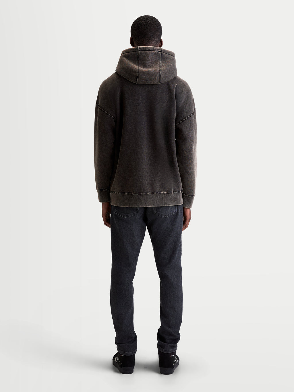 Alpinestars sweat à capuche Infinite Washed Oversize, pull sportswear décontracté unisexe, noir délavé, polaire avec finition effet neige, vue de dos montrant la coupe ample, le détail de la capuche et l'ourlet côtelé.