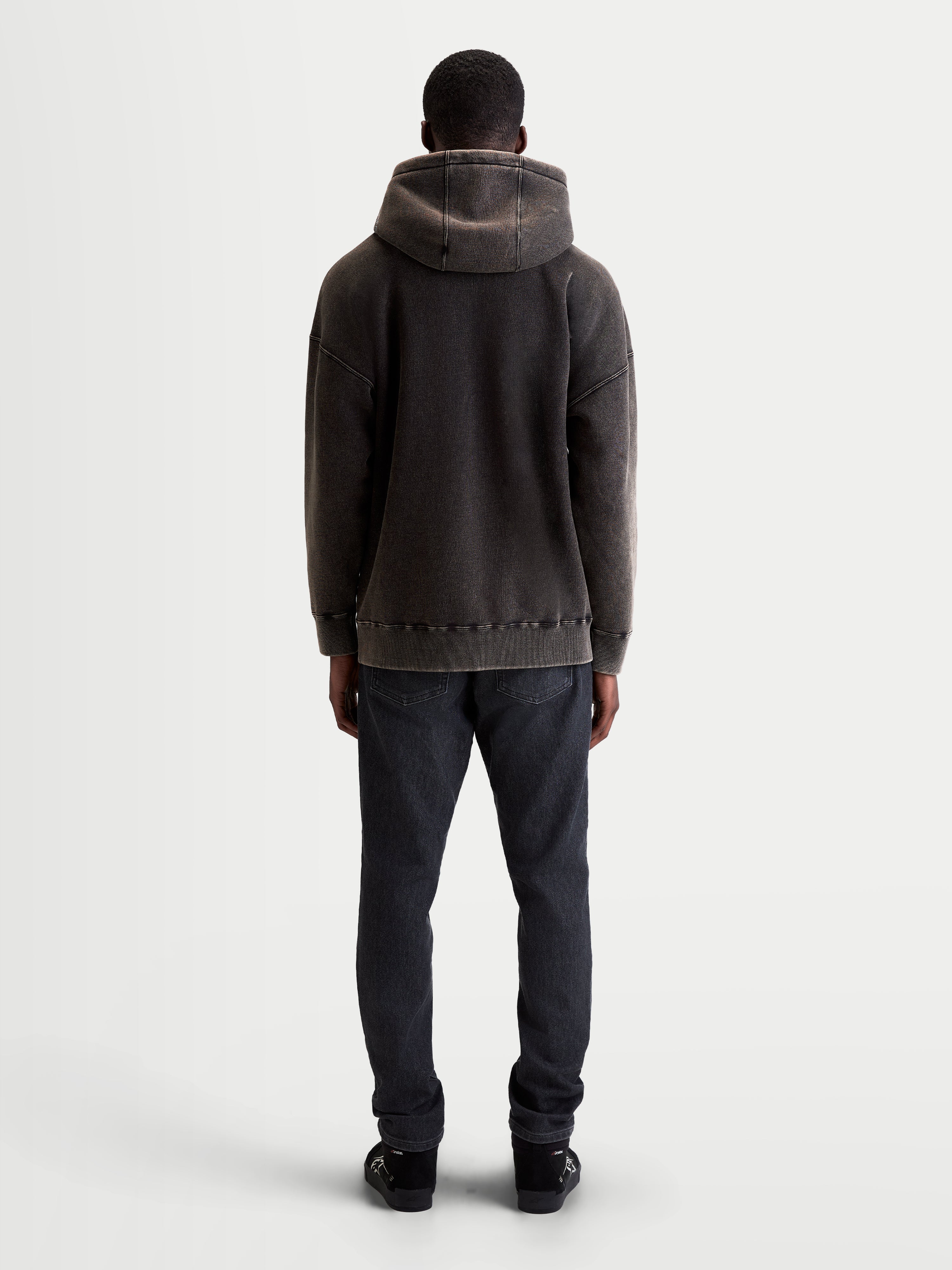 Alpinestars sweat à capuche Infinite Washed Oversize, pull sportswear décontracté unisexe, noir délavé, polaire avec finition effet neige, vue de dos montrant la coupe ample, le détail de la capuche et l'ourlet côtelé.