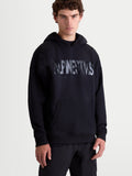 Alpinestars sweat à capuche Shaw Oversized, sweat à capuche de sportswear pour homme, noir, coupe ample et décontractée, logo texturé sur la poitrine, poche kangourou et capuche doublée, conçu en polaire de coton et polyester recyclé, vue de face sur modèle.