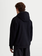 Alpinestars Shaw Oversized, sweat à capuche de sportswear pour homme et femme, noir, vue de dos montrant la coupe ample décontractée, polaire douce en mélange de coton et polyester recyclé avec finitions côtelées