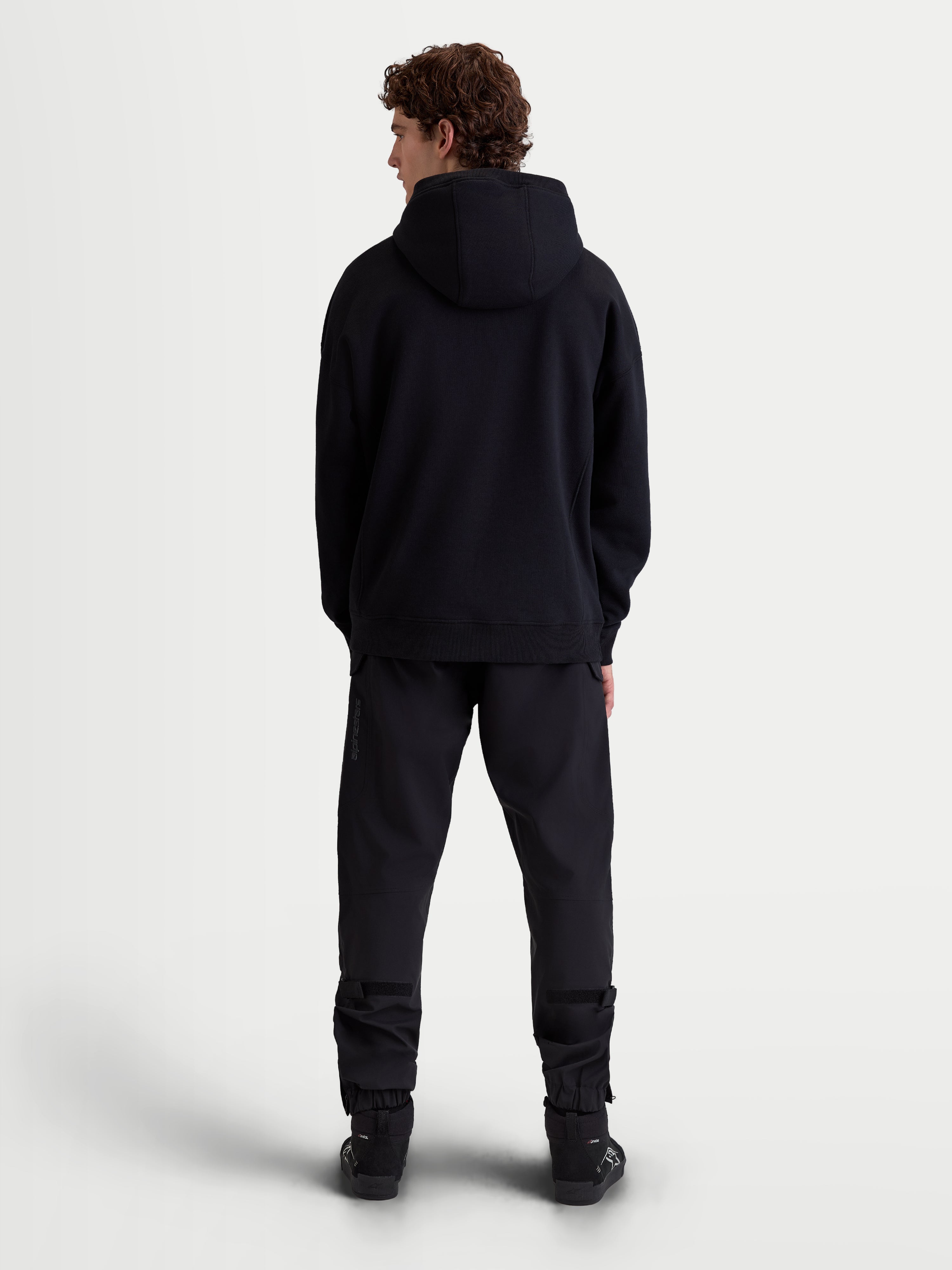 Alpinestars sweat à capuche Shaw Oversized, hoodie sportswear noir, vue de dos sur modèle, silhouette ample décontractée avec capuche doublée et finitions côtelées, en polaire douce.