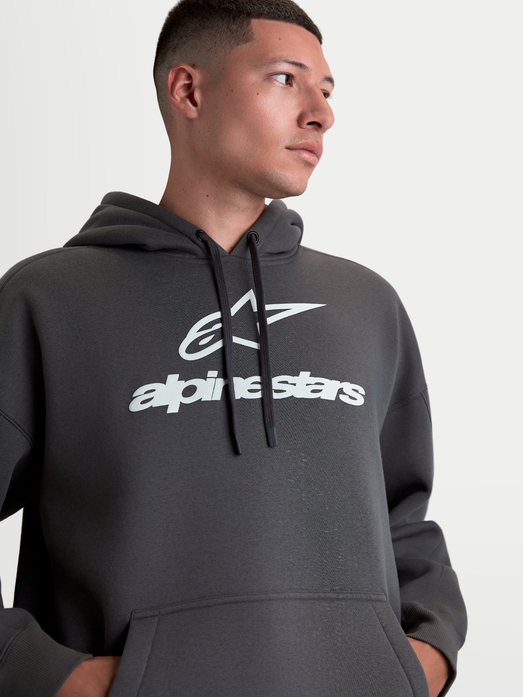Alpinestars Prelude oversized hoodie, unisex sportswear fleece pullover, grijs met wit puff-print logo, ontspannen oversized pasvorm, voorzien van kangoeroezak en capuchon met trekkoord.