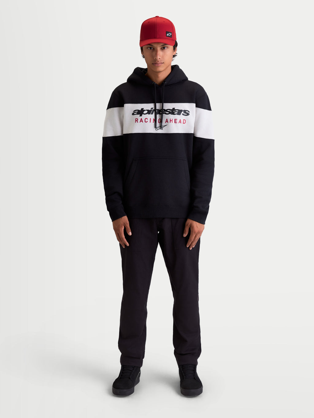 Alpinestars sweat à capuche Cubic, sweat à capuche sportswear pour homme, noir et blanc, porté par un modèle, présentant un design à blocs de couleur avec le logo Racing Ahead sur la poitrine, en polaire douce pour un style décontracté.