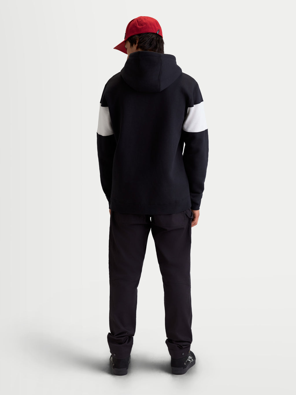Alpinestars Sweat à capuche Cubic, sweat à capuche sportswear mixte, noir et blanc, vue de dos sur modèle portant une casquette rouge, manches avec blocs de couleurs contrastés, construction en polaire de coton mélangé.