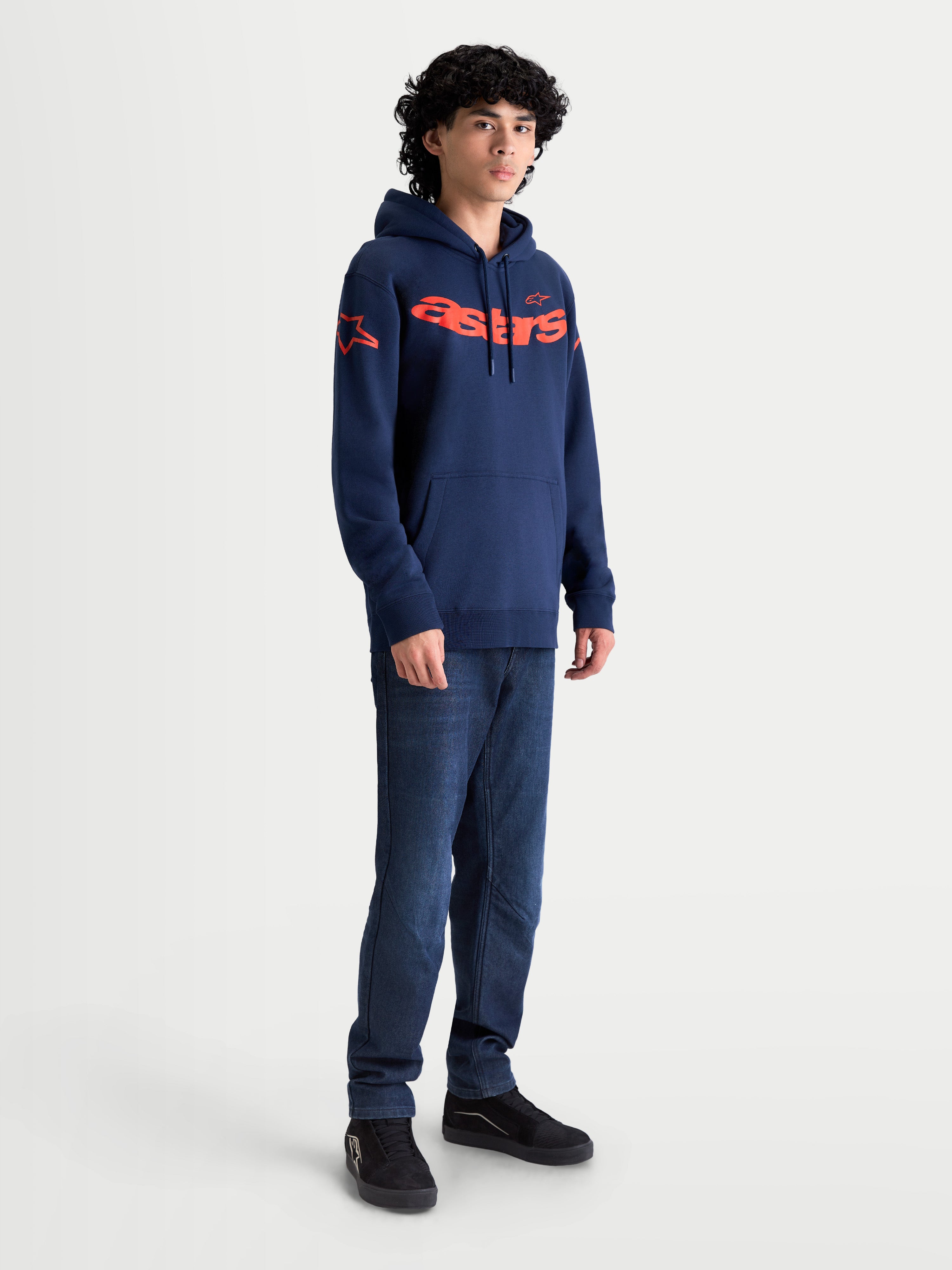 Alpinestars Velocifier, sweat à capuche sportswear pour homme, bleu marine et orange, avec logo Astars sur la poitrine et les épaules, en polaire de coton et polyester recyclé, présenté sur mannequin pour un style décontracté inspiré du sport automobile.