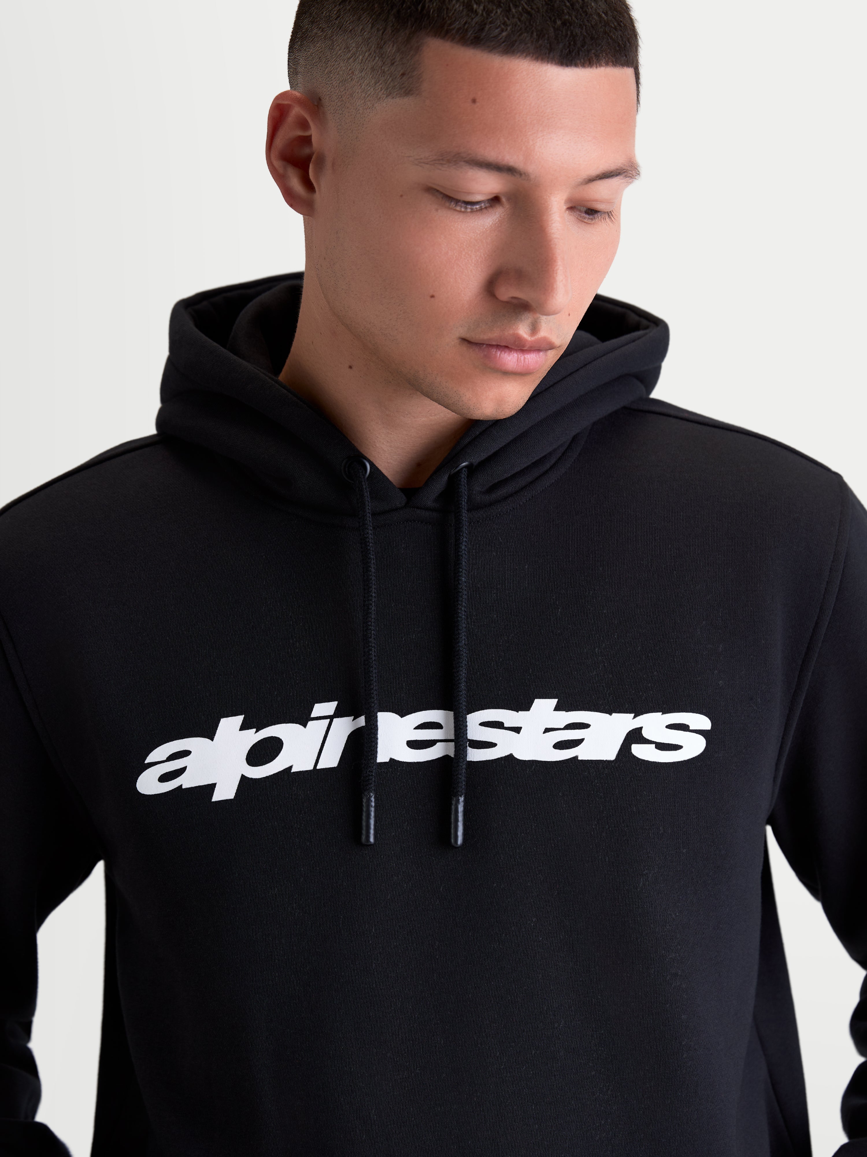Alpinestars Sweat À Capuche Race Wordmark, sweat à capuche sportswear pour homme, noir avec logo wordmark blanc sur la poitrine, capuche doublée et cordons avec embouts trempés, confectionné en polaire de coton et polyester recyclé.