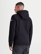 Alpinestars Sweat à capuche Race Wordmark, sweat à capuche sportswear pour homme, noir et blanc, vue de dos sur un modèle, logo Ageless blanc sur la manche gauche, capuche doublée, poignets côtelés, polaire en coton et polyester recyclé
