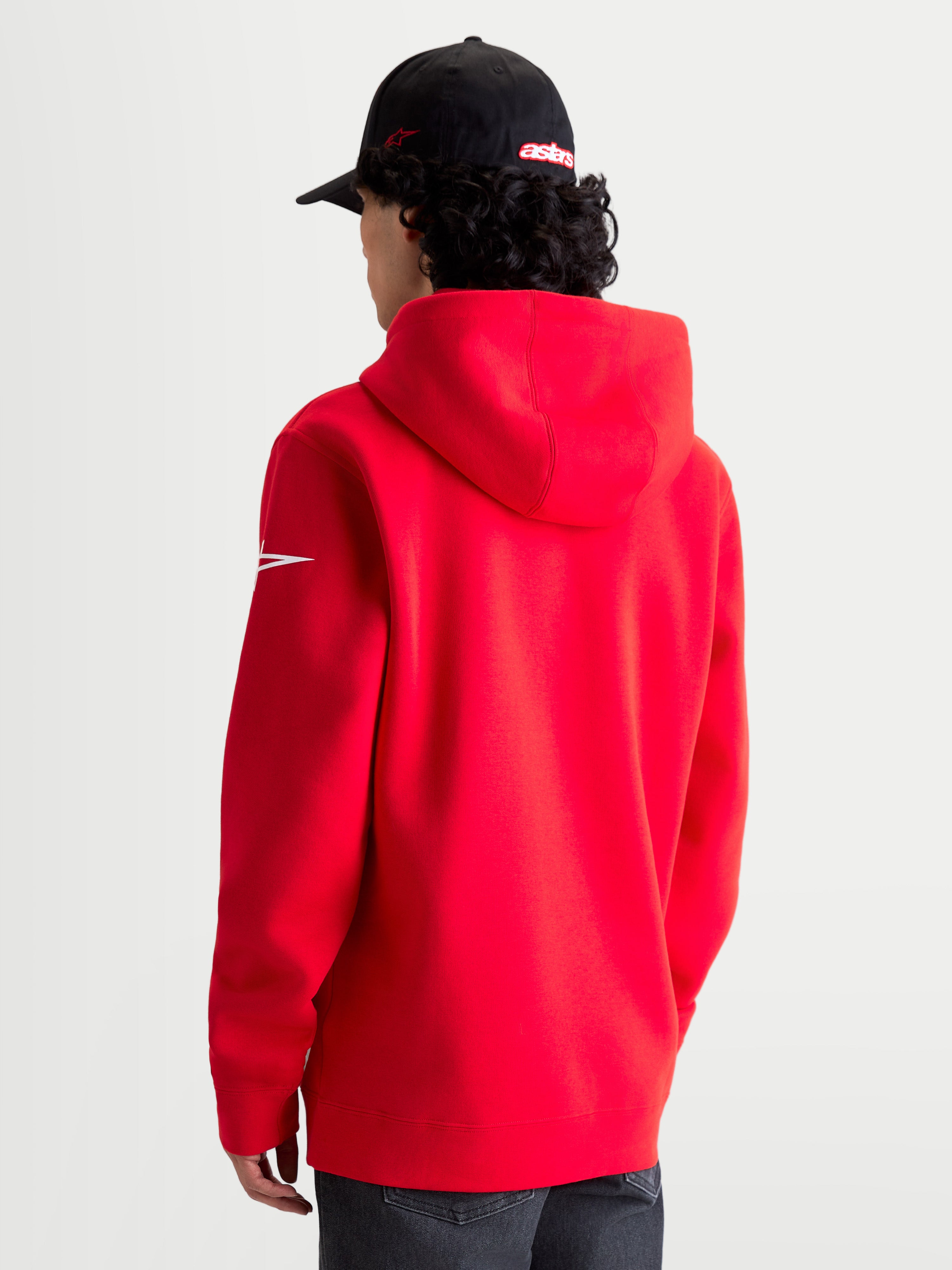 Alpinestars Race Wordmark Hoodie, sportswear hoodie van fleece, rood en wit, achteraanzicht op model met de capuchon en het witte Ageless-logo op de mouw, premium katoen en gerecycled polyester voor een casual motorsportstijl.