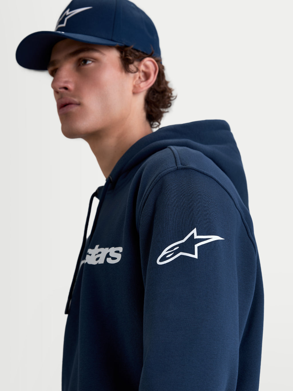Alpinestars Race Wordmark Hoodie, Men's Sportswear Pullover Fleece in Navy Blue and White, featuring the white Ageless logo on the sleeve and Race Wordmark on the chest, lifestyle on-model view.