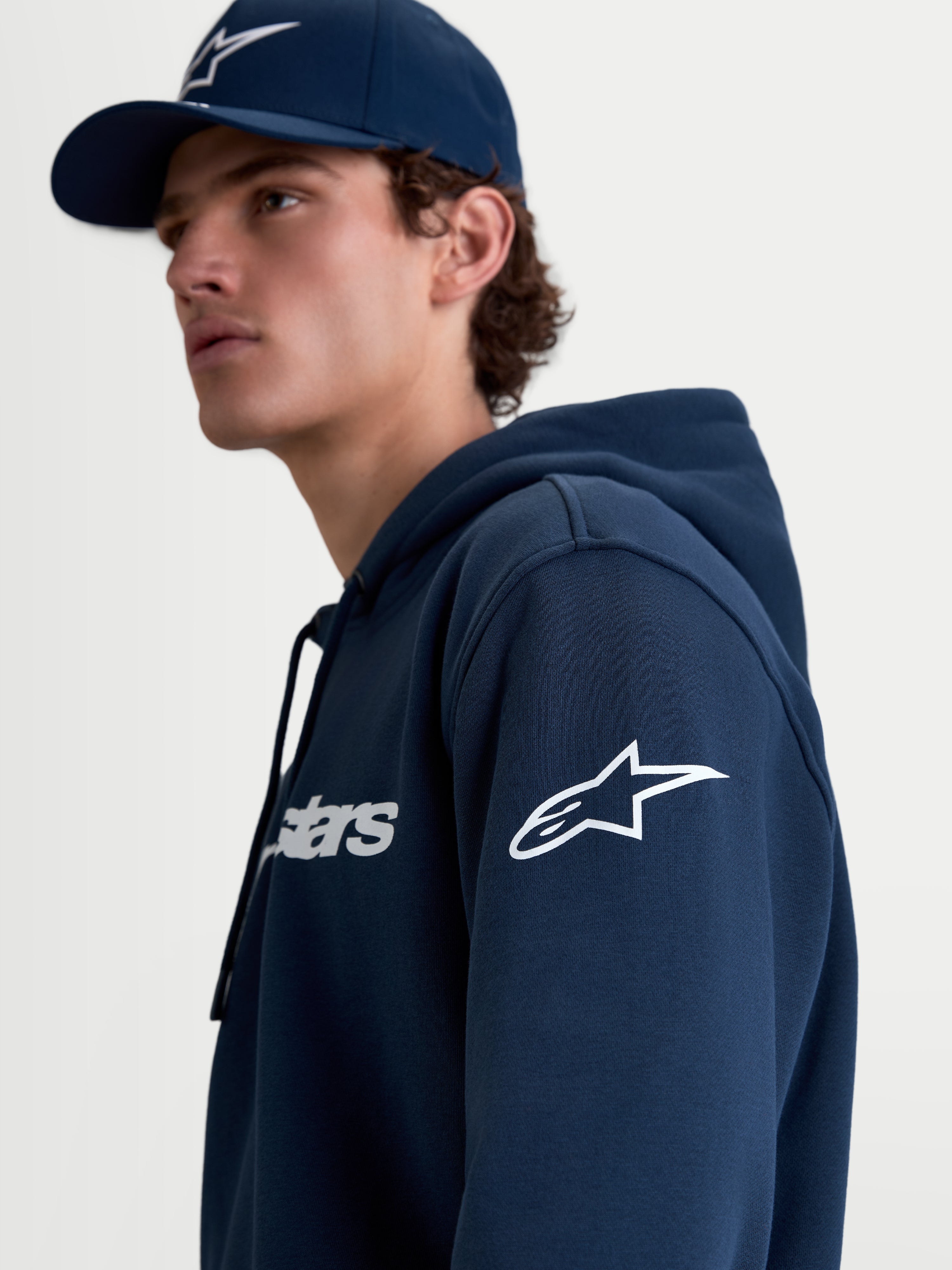 Alpinestars Race Wordmark Hoodie, Men's Sportswear Pullover Fleece in Navy Blue and White, featuring the white Ageless logo on the sleeve and Race Wordmark on the chest, lifestyle on-model view.