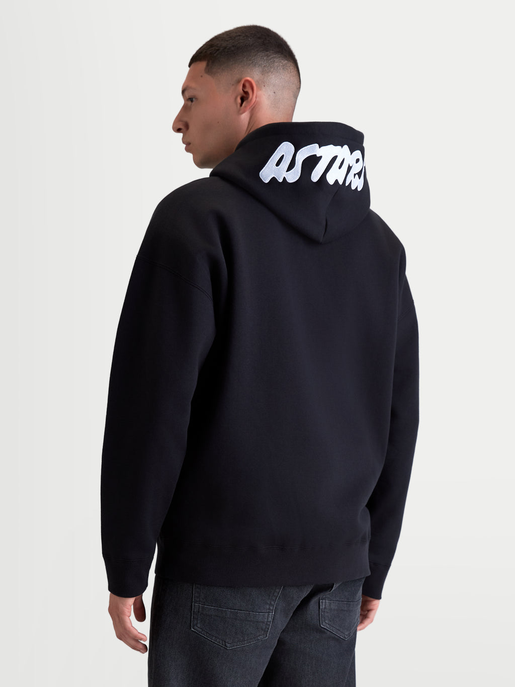 Alpinestars Sweat à capuche Pioneer Oversize, sweat de sportswear pour homme, noir et blanc, coupe oversize décontractée, logo ASTARS blanc brodé sur la capuche, polaire en coton premium, vue de dos sur modèle