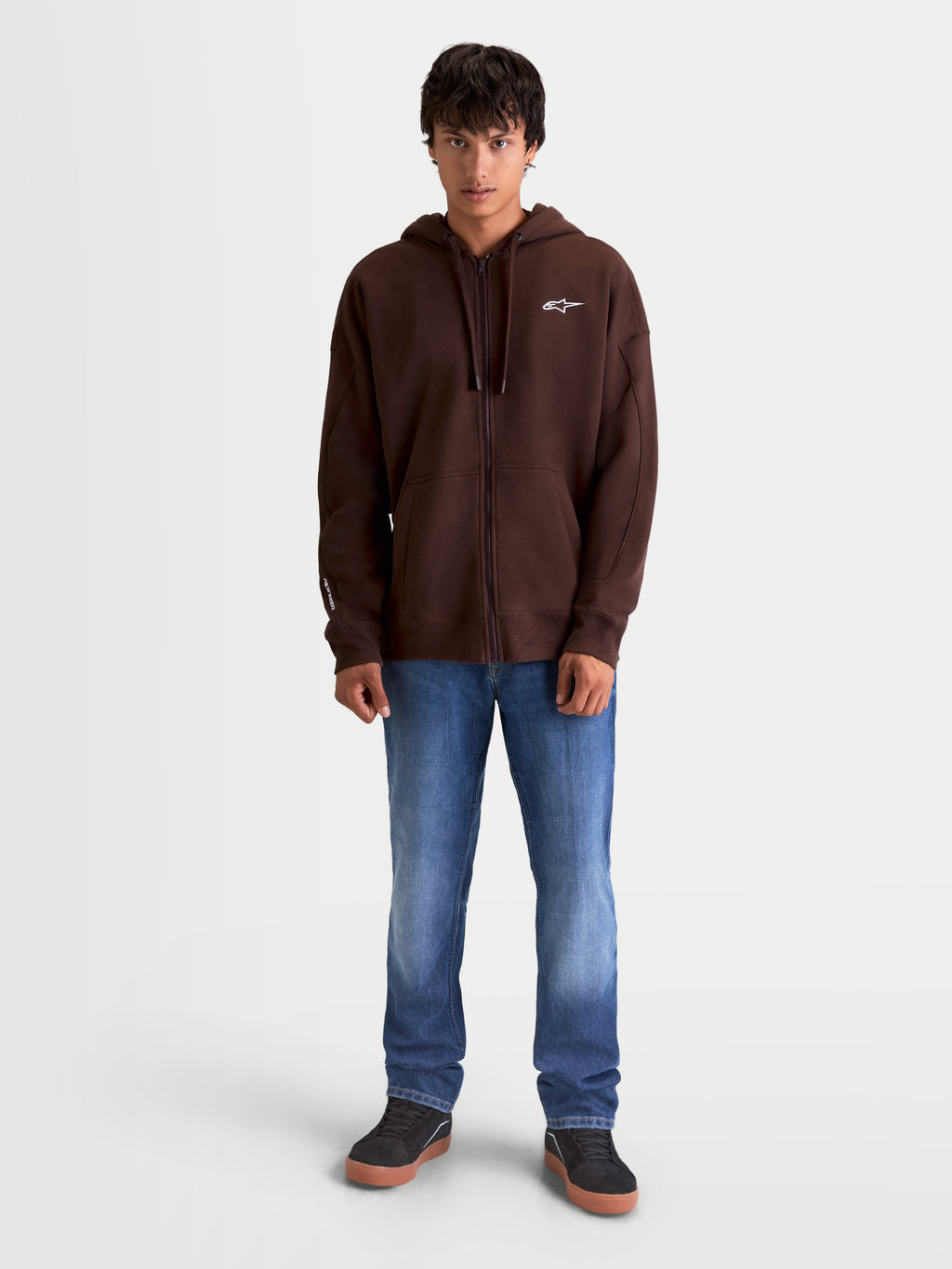 Alpinestars sweat à capuche Entity Oversized, veste à capuche marron pour homme, style sportswear décontracté, polaire zippée avec logo Astars blanc brodé et fermeture éclair Vislon, porté par un modèle.