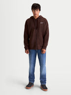 Alpinestars sweat à capuche Entity Oversized, veste à capuche marron pour homme, style sportswear décontracté, polaire zippée avec logo Astars blanc brodé et fermeture éclair Vislon, porté par un modèle.