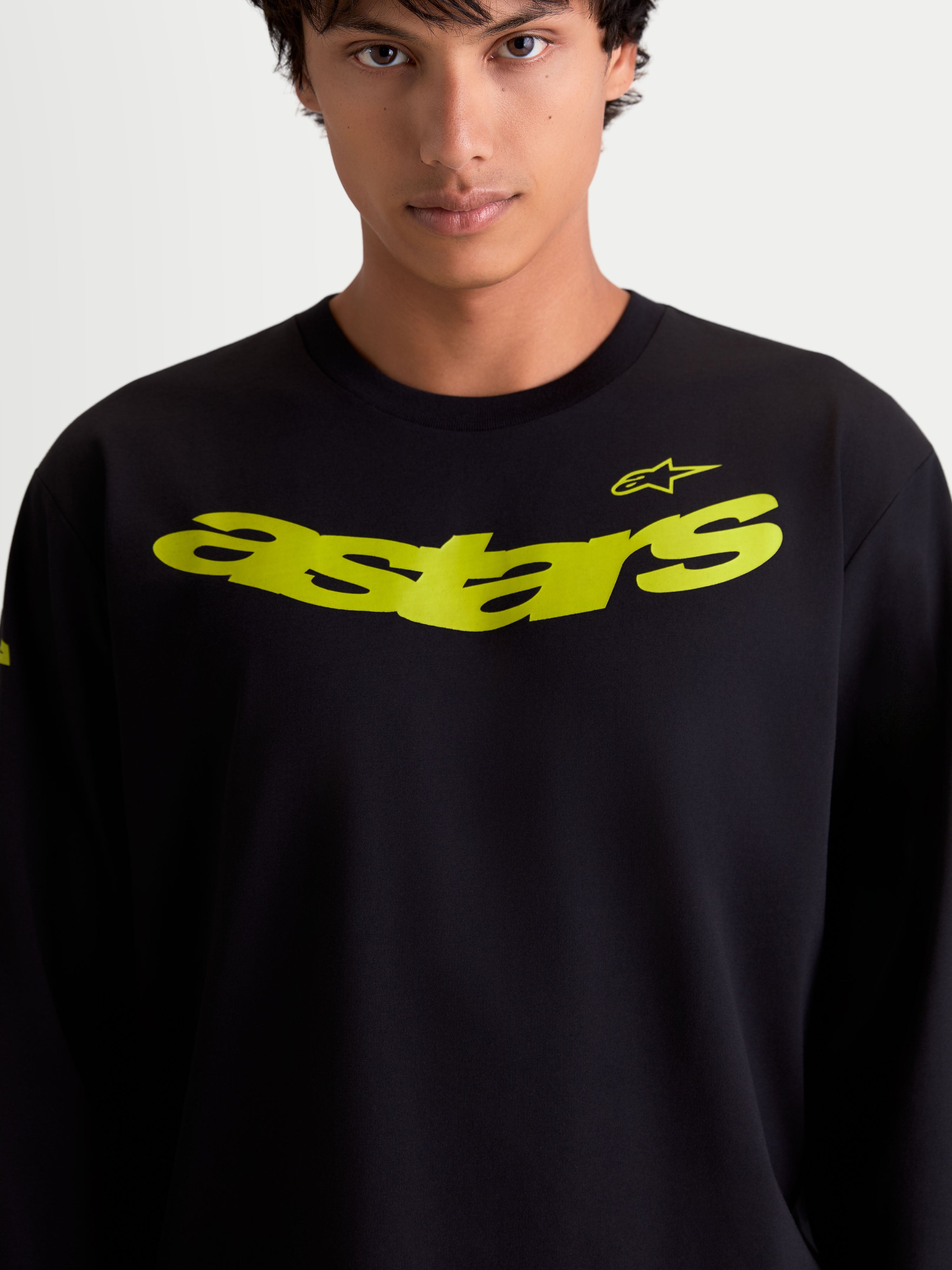 Alpinestars Velocifier CSF T-shirt met lange mouwen op model, zwart met gele gebogen Astars-graphic op de borst en schouderlogo, katoenrijke performance-mix, casual sportswear.