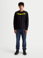 Alpinestars Velocifier CSF t-shirt met lange mouwen, zwart en geel, motorsport-geïnspireerde casual sportswear, gebogen Astars-graphic op de borst, op model gedragen.