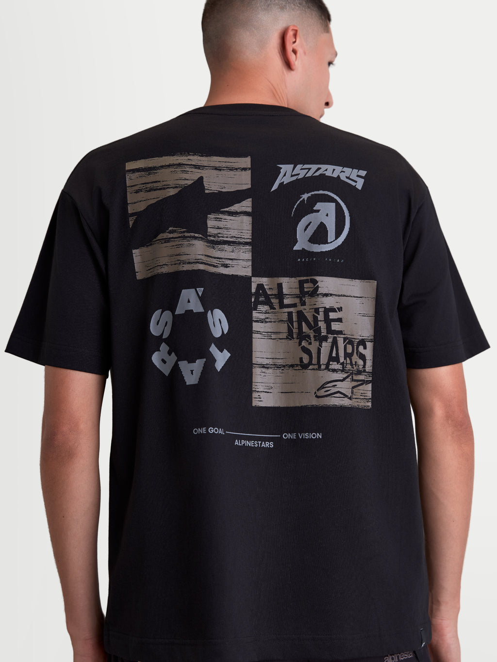 Alpinestars Checkback Oversized CSF t-shirt, zwart sportswear t-shirt met korte mouwen, achteraanzicht op model met een grote grijze graphic, Astars-logo's en 'One Goal One Vision' slogan, oversized fit, katoen-polyester mix.