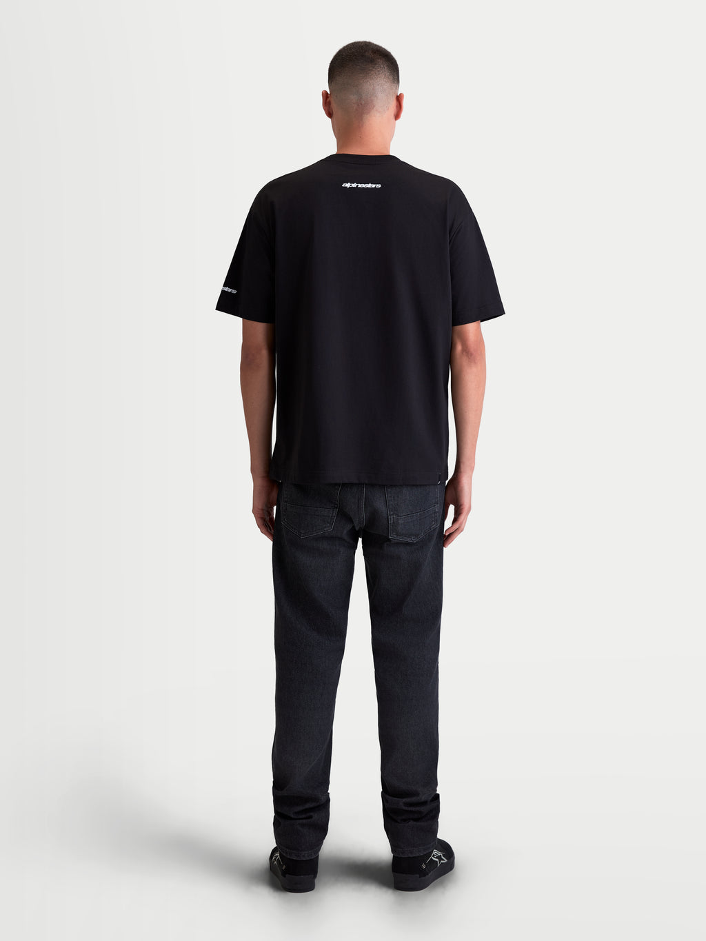 Alpinestars Mandate Oversized CSF, t-shirt sportswear à manches courtes unisexe, noir, coupe ample et décontractée, mélange de coton et polyester, vue de dos sur mannequin avec graphismes blancs en impression puff sur le col et la manche.