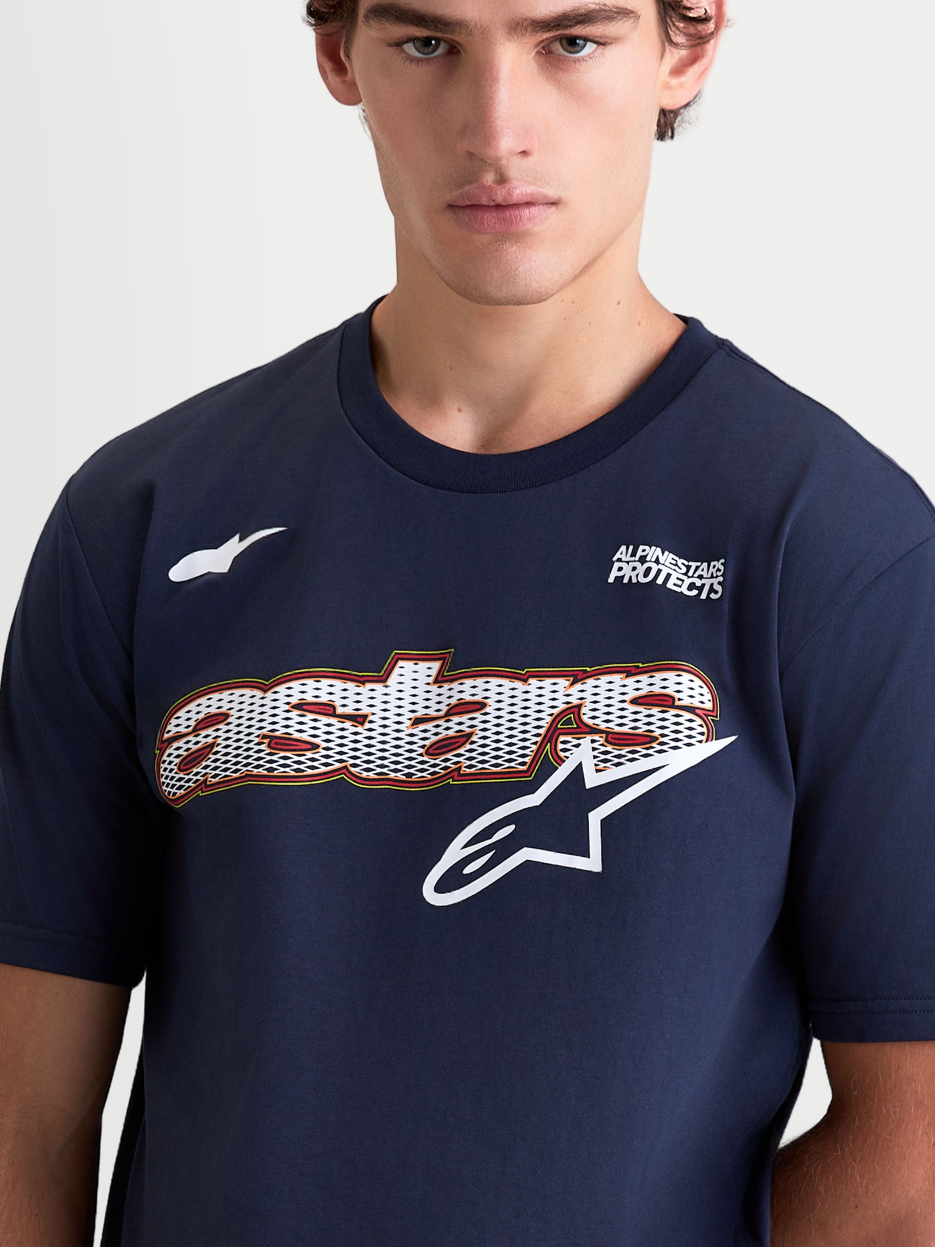 Alpinestars Cypress CSF, t-shirt sportswear à manches courtes pour homme, bleu marine et blanc, graphique Astars avec remplissage mesh et logo sur la poitrine, texte Alpinestars Protects, mélange de coton et polyester, gros plan sur modèle