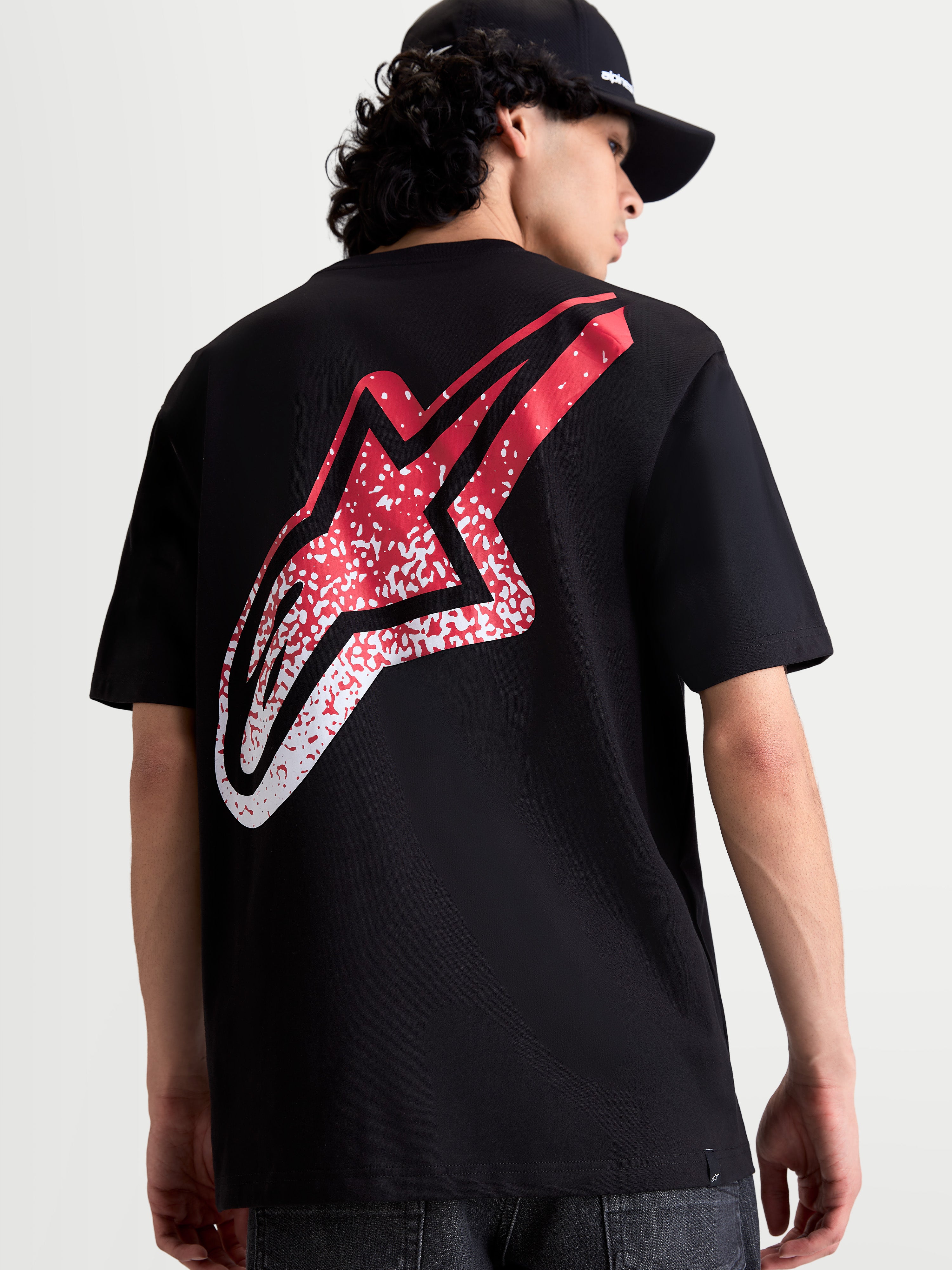 Alpinestars Meteor CSF t-shirt met korte mouwen, zwart, achteraanzicht op model met een groot rood en wit MX-geïnspireerd Astars-logo met kleurverloop op de rug, casual motorsportkleding.
