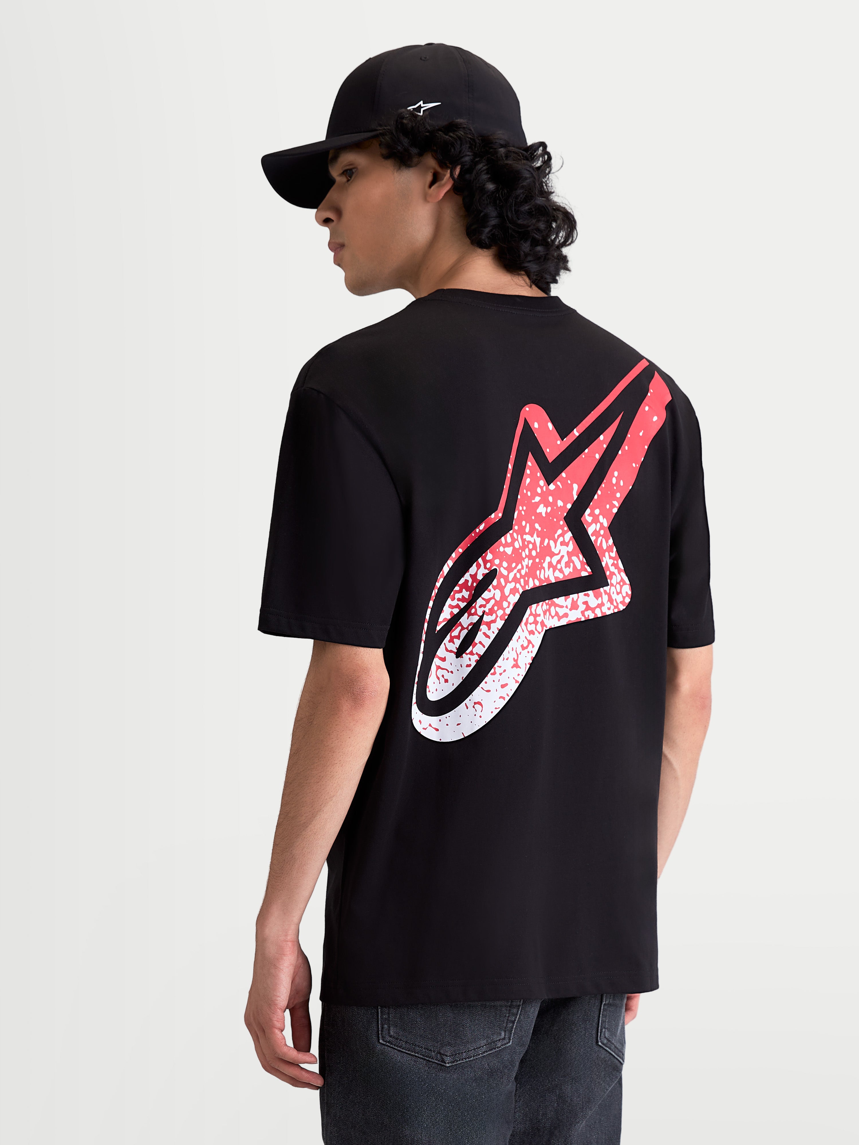 Alpinestars Meteor CSF t-shirt, herensportswear met korte mouwen, achteraanzicht op model, zwart en rood, groot MX-geïnspireerd Astars-logo met kleurverloop op de rug, zachte katoen-polyestermix.