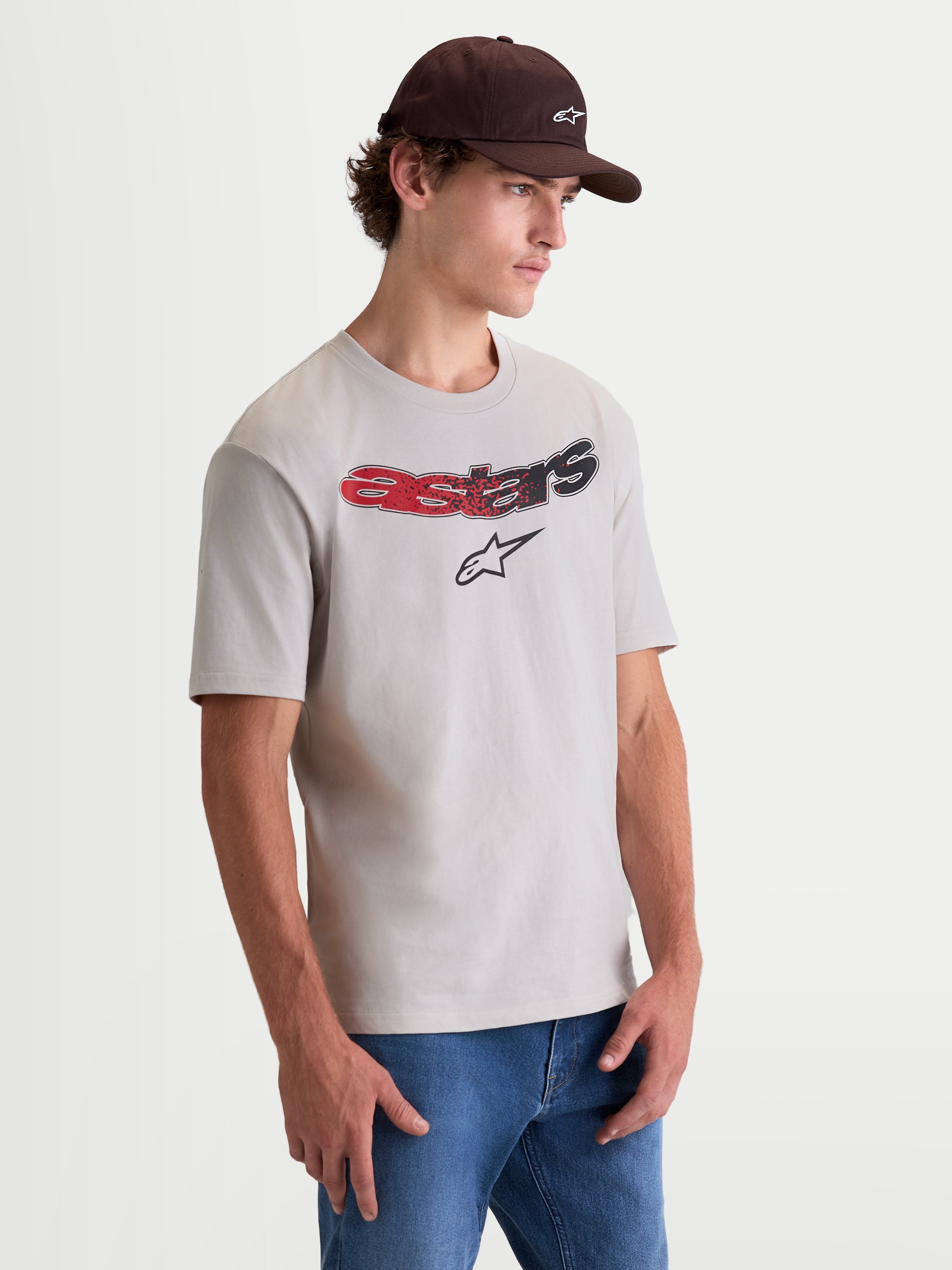 Alpinestars T-Shirt Elliptogrit CSF, t-shirt à manches courtes pour homme, gris ciment avec logo Astars en dégradé rouge et noir sur la poitrine, porté par un modèle, style sportswear décontracté.