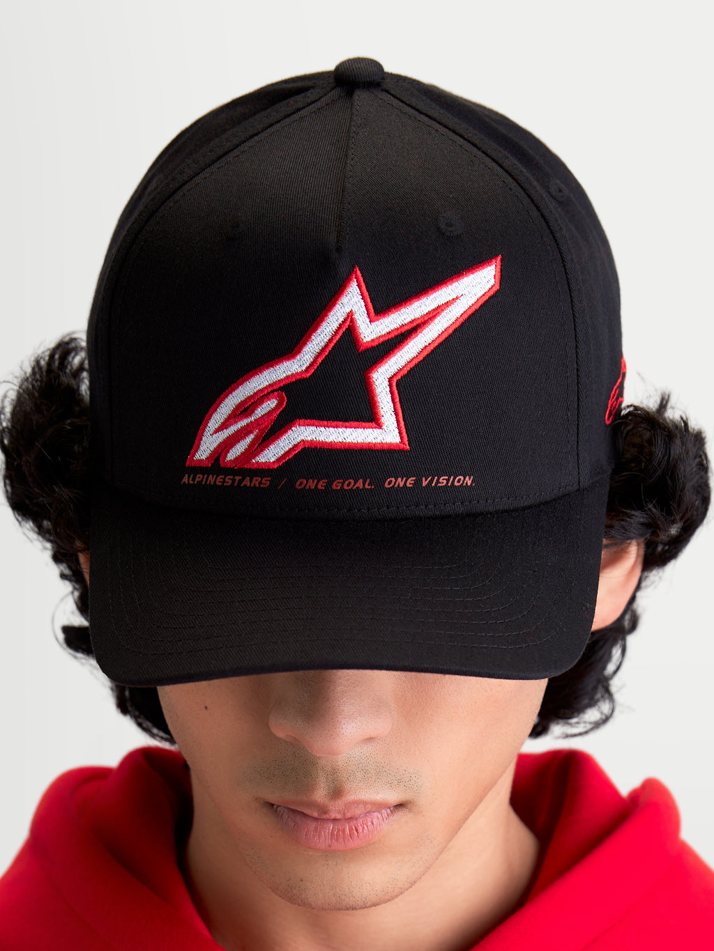 Alpinestars casquette Lineout, casquette de sportswear pour homme et femme, noire avec logo Astars brodé en rouge et blanc et slogan One Goal One Vision, visière incurvée, couronne structurée, construction en textile, portée par un modèle