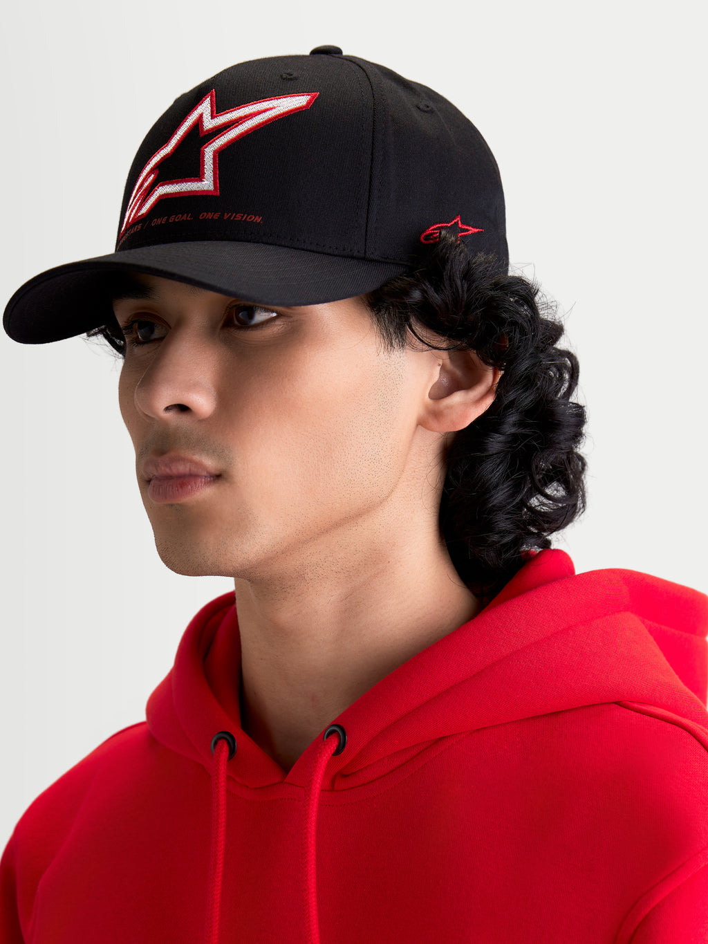 Alpinestars casquette Lineout, casquette de baseball sportswear noire, visière incurvée, couronne structurée avec logo Astars brodé rouge et blanc et marquage latéral, portée par un modèle.