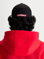 Alpinestars Casquette Lineout, casquette de baseball sportswear noire et rouge, vue arrière sur modèle avec logo Astars brodé, couronne structurée, construction en tissu sergé.