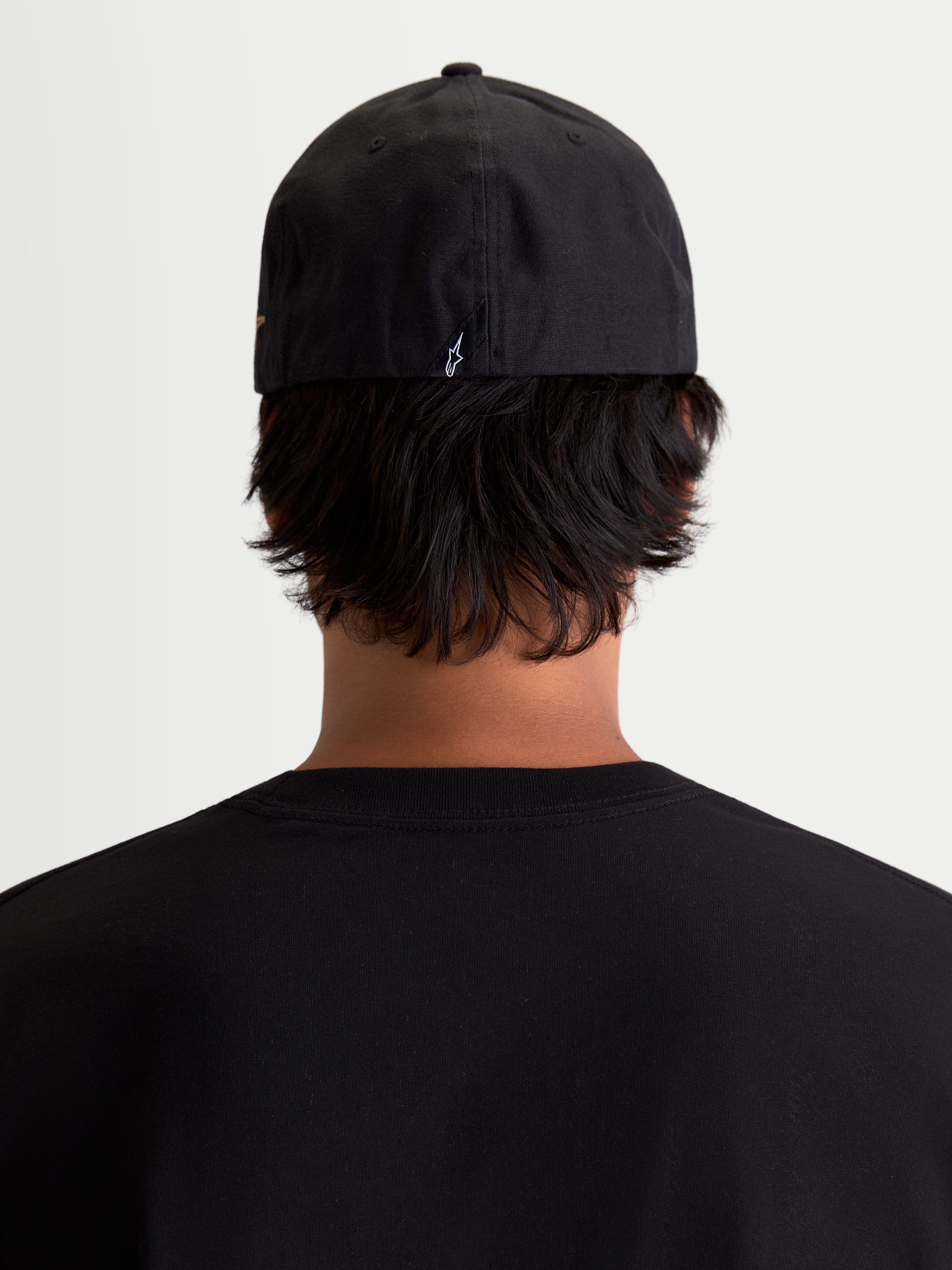 Alpinestars Casquette County Canvas, casquette sportswear noire, vue de dos sur mannequin avec ajustement flex-back et petit logo Astars brodé, matériau en toile oxford peignée