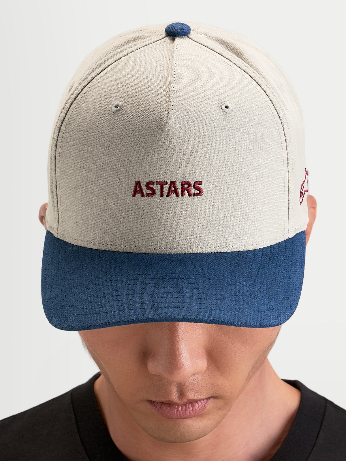 Alpinestars County Canvas pet, sportswear pet in zandkleurig en blauw, gebogen klep, gestructureerde kroon en geborduurd Astars logo op de voorzijde gedragen door model