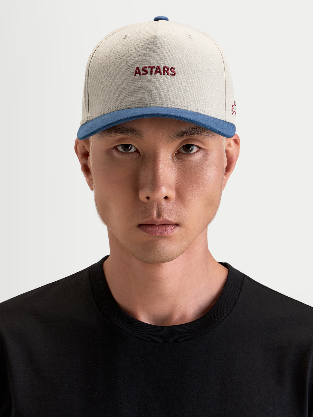 Alpinestars County Canvas pet, casual sportswear pet gedragen door een model, zandkleurig en blauw met geborduurde Astars-logo's op de voor- en zijkant, gestructureerde kroon en gebogen klep