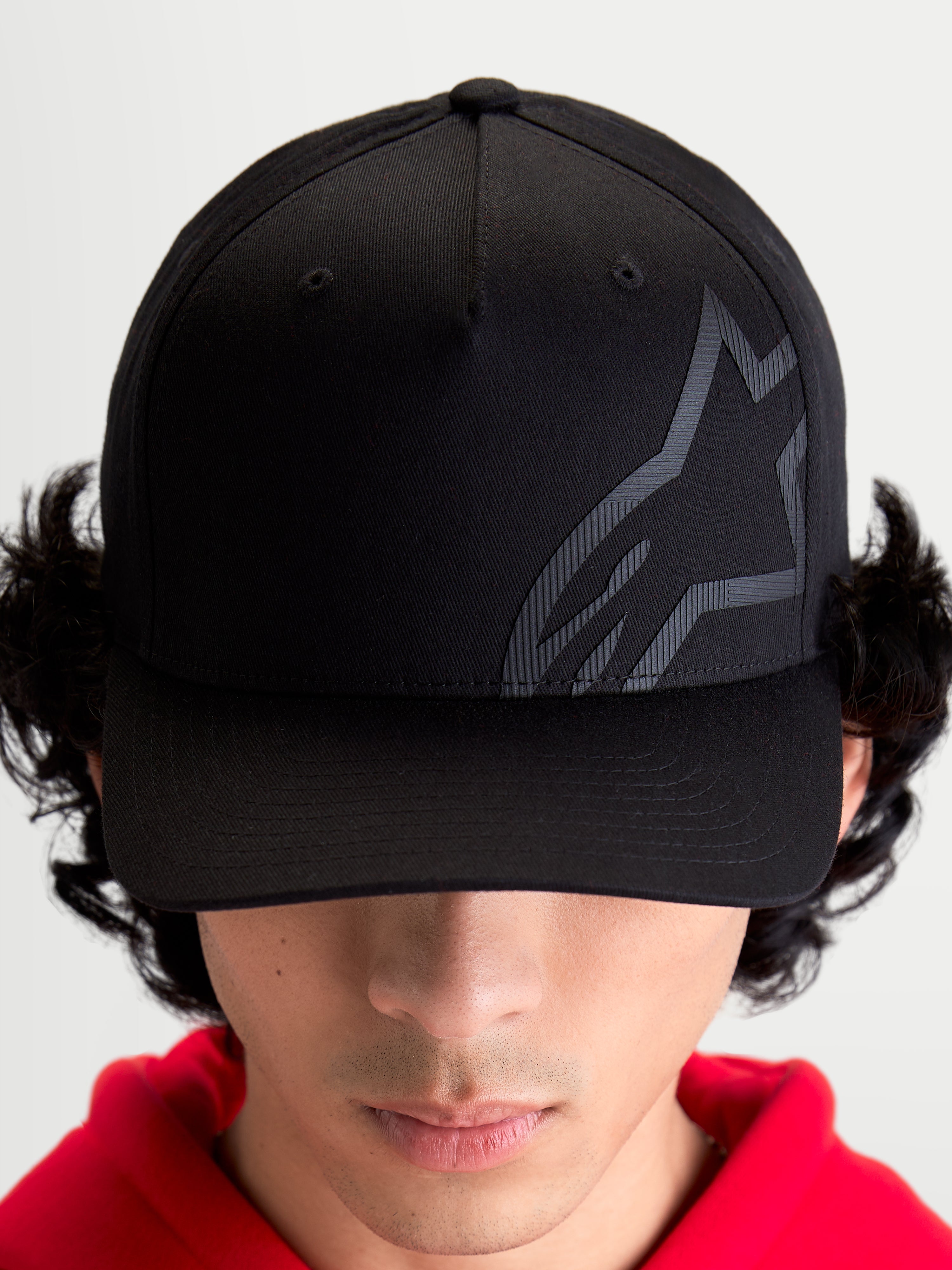 Alpinestars Casquette Maze, casquette de baseball sportswear inspirée du sport automobile, unisexe, noire, tissu sergé avec couronne structurée, visière incurvée et logo Astars Corp Shift texturé ton sur ton, vue de face sur modèle.