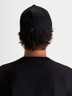 Alpinestars Arclight, casquette sportswear noire, vue de dos sur modèle avec un petit logo Astars blanc à l'arrière, couronne structurée et construction flex back en sergé de coton durable.