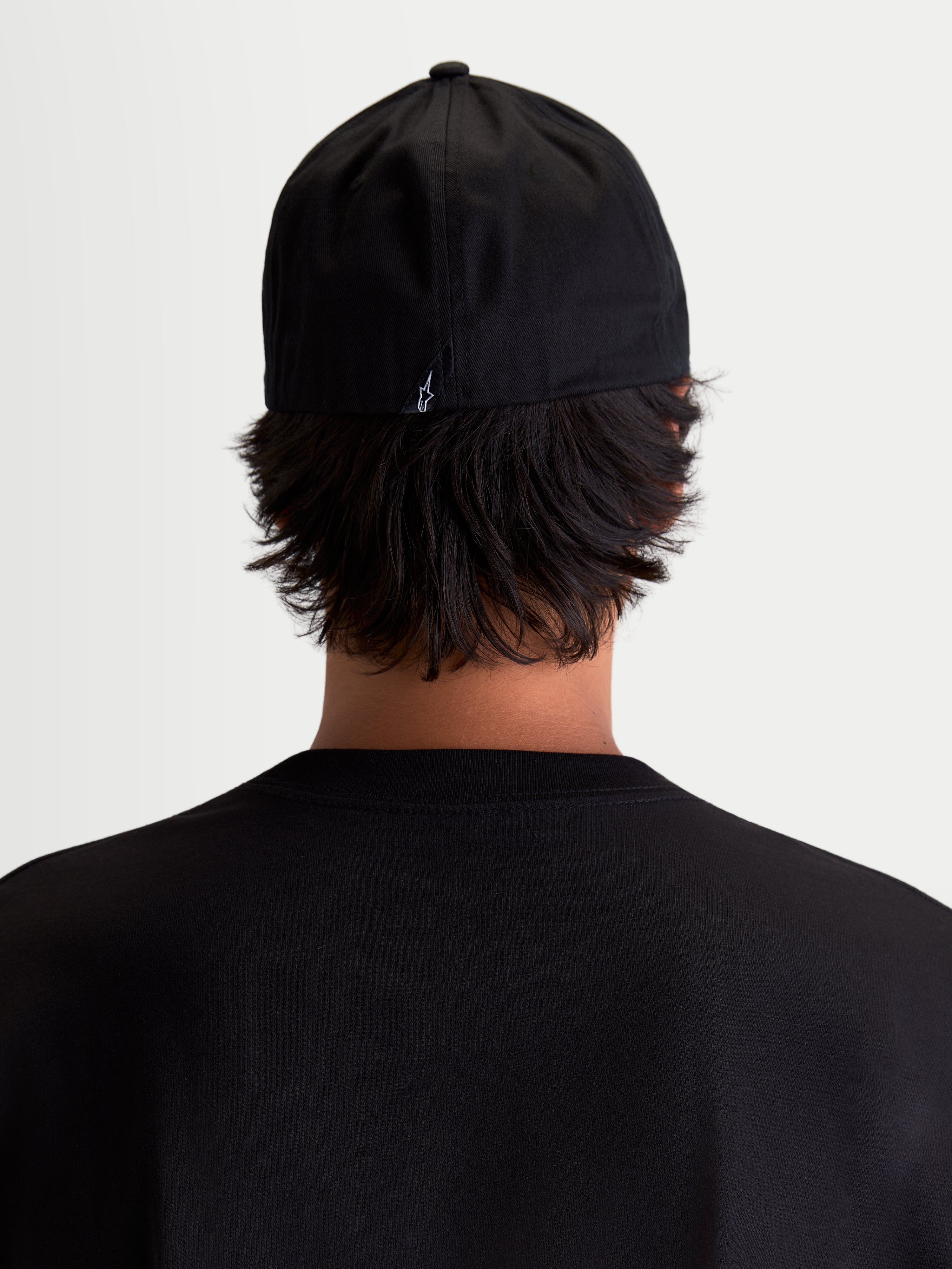 Alpinestars Arclight, casquette sportswear noire, vue de dos sur modèle avec un petit logo Astars blanc à l'arrière, couronne structurée et construction flex back en sergé de coton durable.