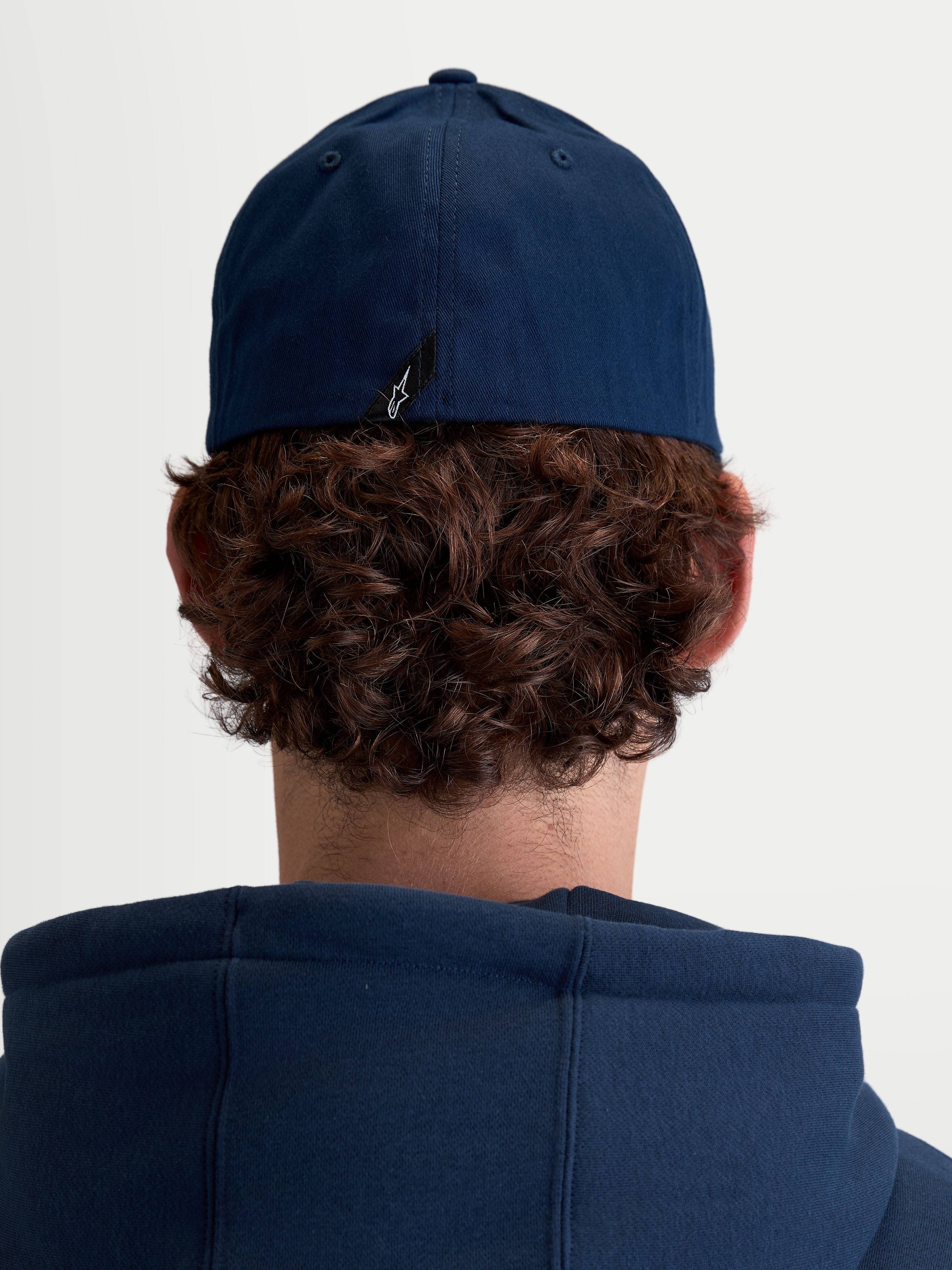 Alpinestars Arclight, casquette de sportswear unisexe, bleu marine, confectionnée en sergé de coton durable avec dos flexible, vue de dos sur modèle montrant le détail de l'étiquette avec le logo Astars.