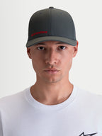 Alpinestars Casquette Points, casquette sportswear à visière incurvée pour homme et femme, gris foncé avec logo Alpinestars rouge, confectionnée en nylon tactel léger avec coupe flex-back, vue de face portée par un modèle