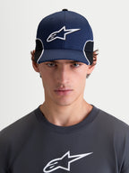 Alpinestars 500 Snapback pet, herensportswear baseballpet, donkerblauw en zwart, gebogen klep, gestructureerde kroon, 3D-geborduurd Astars-logo en witte contrasterende biezen, vooraanzicht op model.