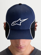 Alpinestars 500 Snapback pet, motorsport-geïnspireerde sportswear pet, unisex, marineblauw en zwart, met een gebogen klep en 3D-geborduurd wit Astars-logo, contrasterende biezen en cut-and-sew details, vooraanzicht op model.