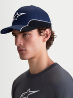 Alpinestars 500 Snapback pet, sportswearpet, unisex, blauw en zwart, duurzaam katoen, voorzien van een gebogen klep en 3D Astars-logo borduursel met witte contrastbiezen, zijaanzicht op model.