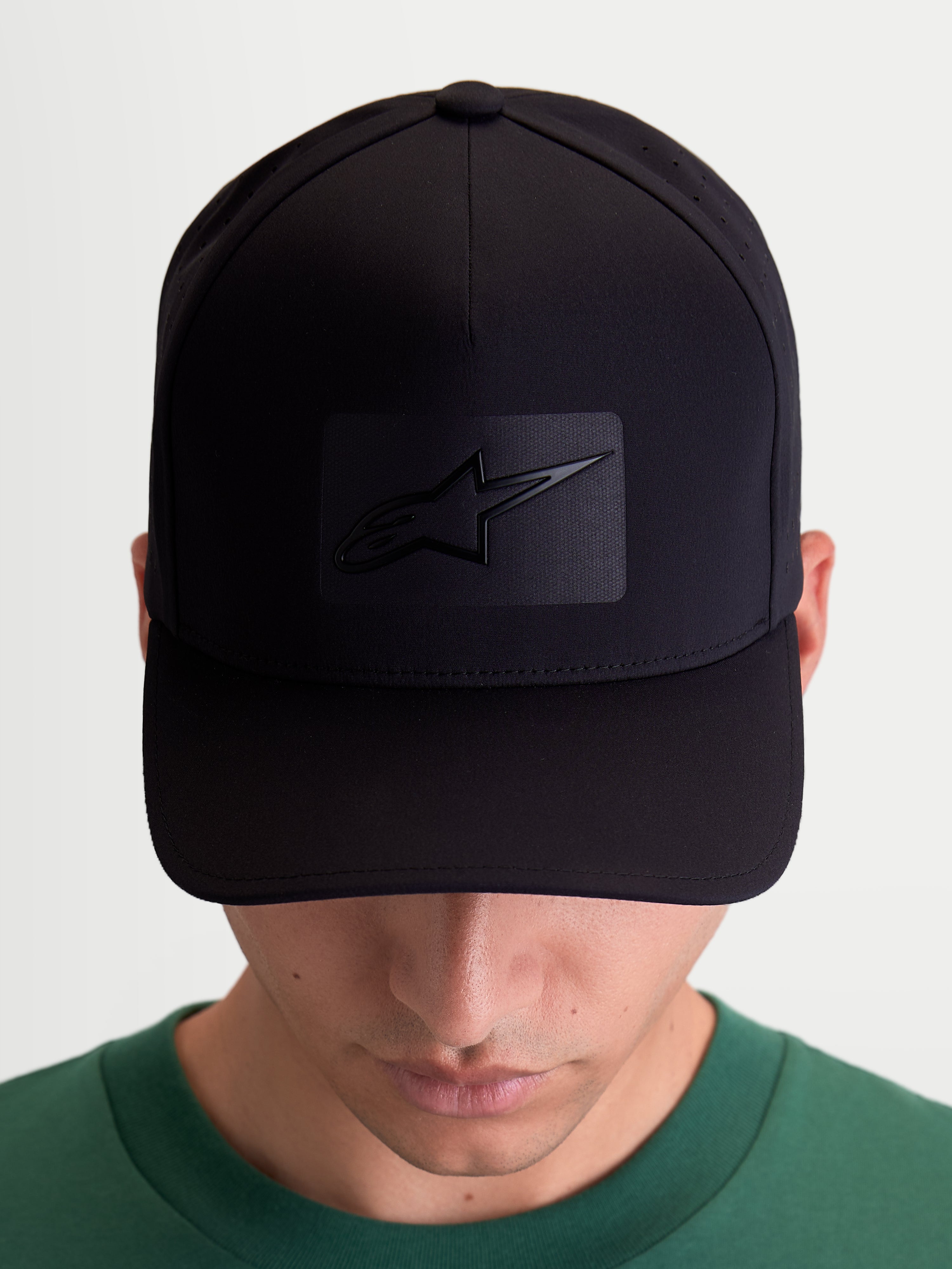 Alpinestars Casquette Algo Perf Adjustable, casquette de baseball sportswear pour homme et femme, noire, tissu technique avec perforations latérales, visière incurvée et couronne structurée, vue de face sur modèle avec logo Astars soudé par ultrasons