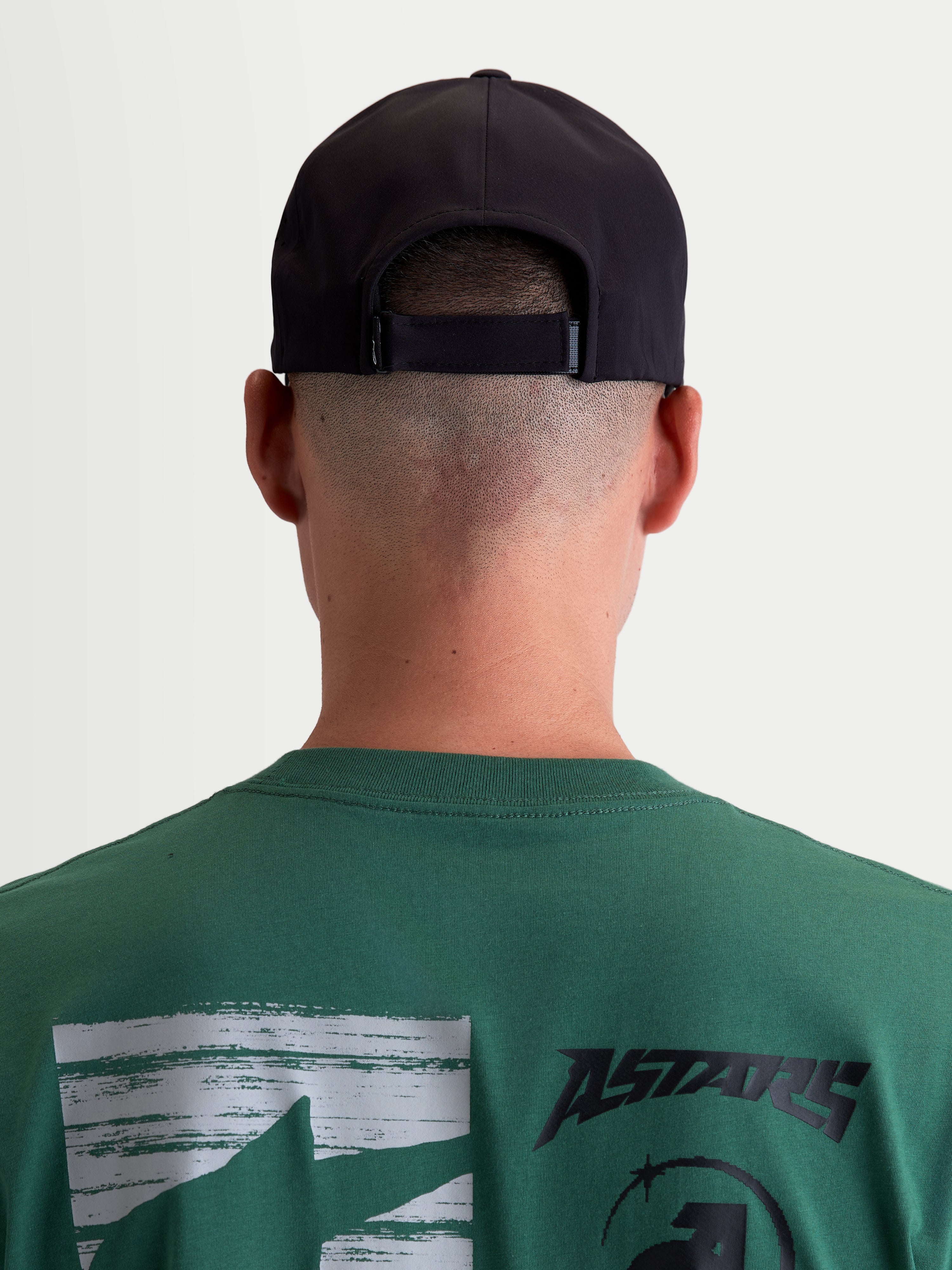Alpinestars Algo Perf Adjustable, casquette de sportswear noire, vue arrière sur modèle montrant la fermeture ajustable, style inspiré du sport automobile, tissu technique, unisexe