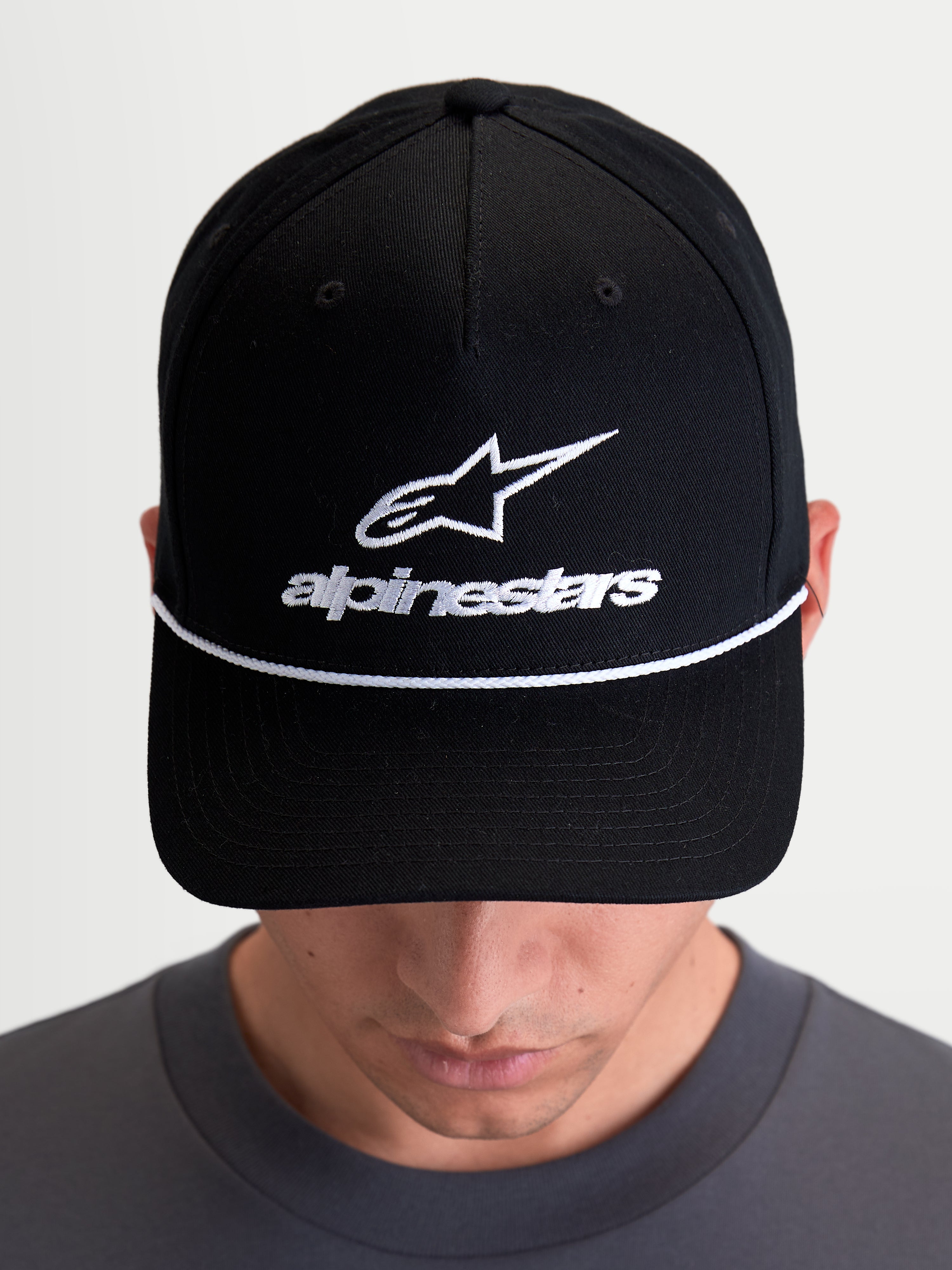 Alpinestars Combo Logo Snapback, casquette sportswear avec couronne structurée et visière courbée, mixte, noire et blanche, broderie frontale du logo Astars et cordelette décorative blanche, vue de face sur modèle