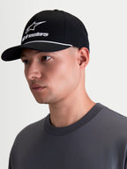 Alpinestars Combo Logo Snapback, casquette de sportswear noire et blanche, visière courbée et couronne structurée, broderie logo Alpinestars combo blanc avec détail de cordelette, vue de profil sur modèle.