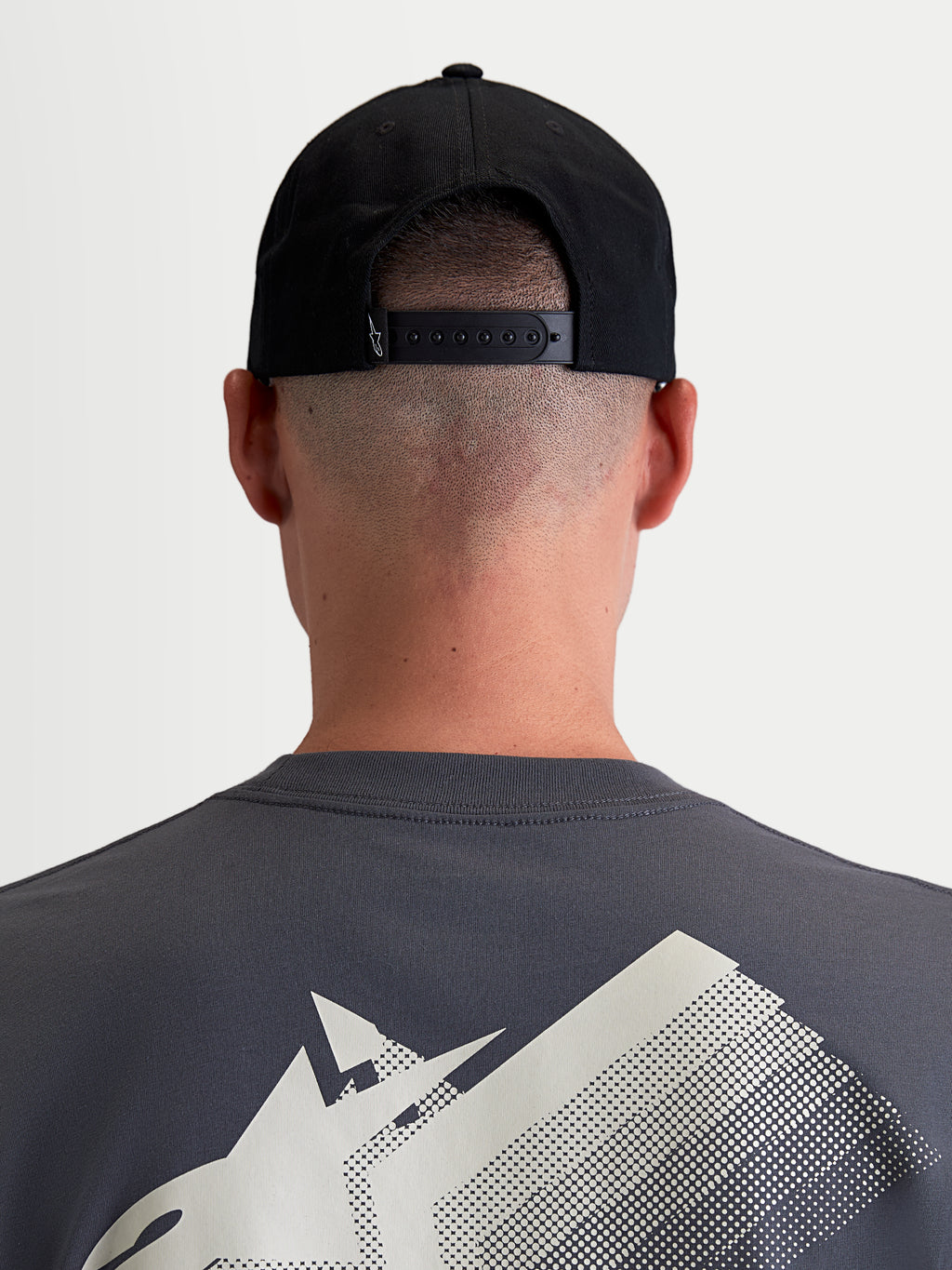 Alpinestars Combo Logo Snapback, casquette sportswear noire en sergé de coton, vue arrière sur modèle montrant la fermeture snapback réglable et un petit logo blanc