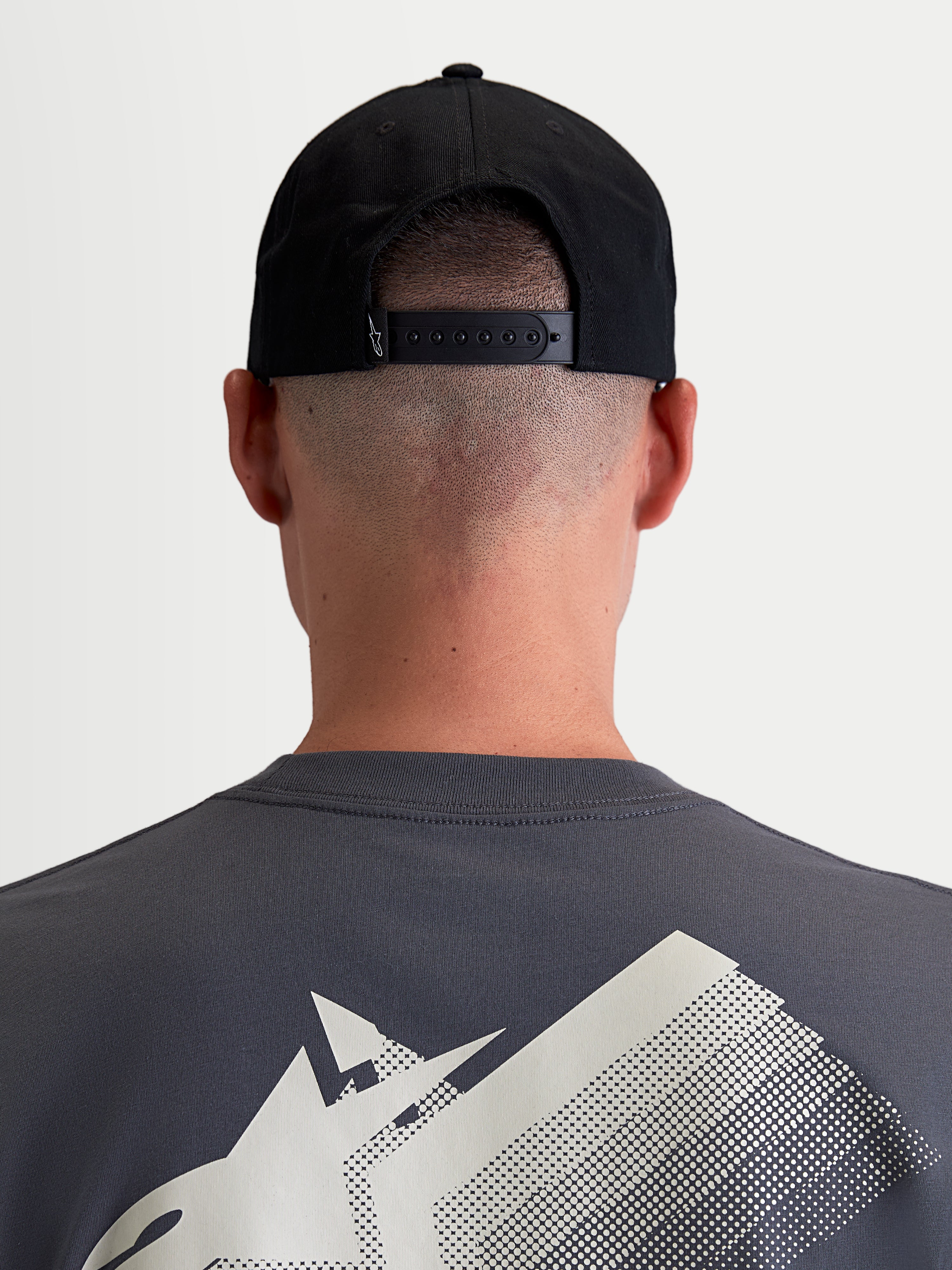 Alpinestars Combo Logo Snapback, casquette sportswear noire en sergé de coton, vue arrière sur modèle montrant la fermeture snapback réglable et un petit logo blanc