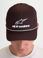 Alpinestars casquette Combo Logo Snapback, casquette de sportswear marron et blanche avec logo Astars brodé sur le devant, visière courbée et couronne structurée, en sergé de coton, portée par un modèle.