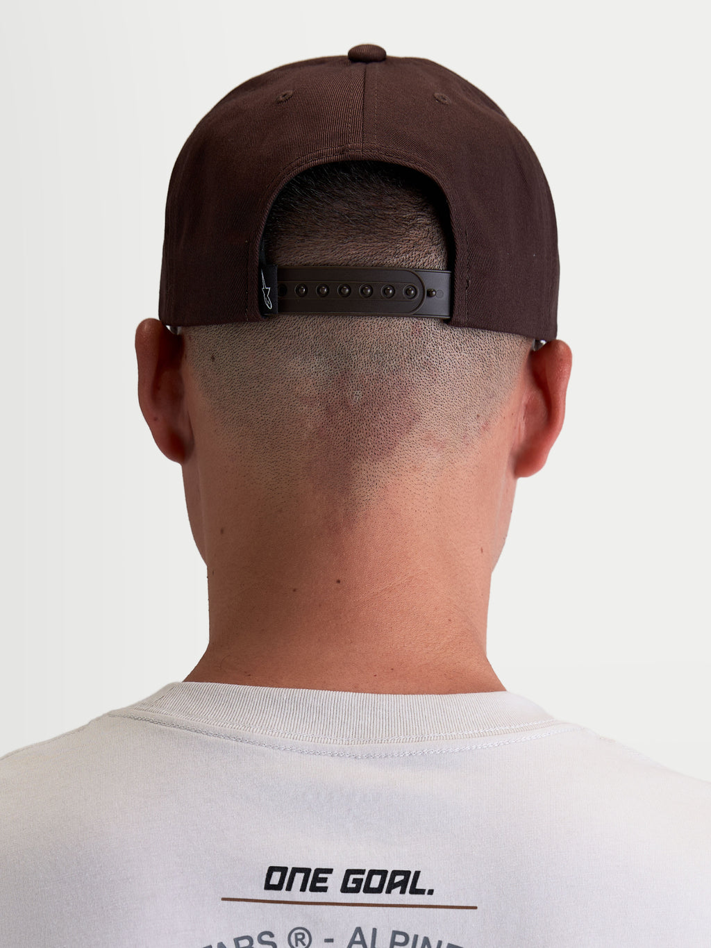 Alpinestars casquette Combo Logo Snapback, casquette de sportswear pour homme et femme, marron, vue arrière sur modèle montrant la fermeture snapback réglable et l'étiquette de marque, style motorsport décontracté.
