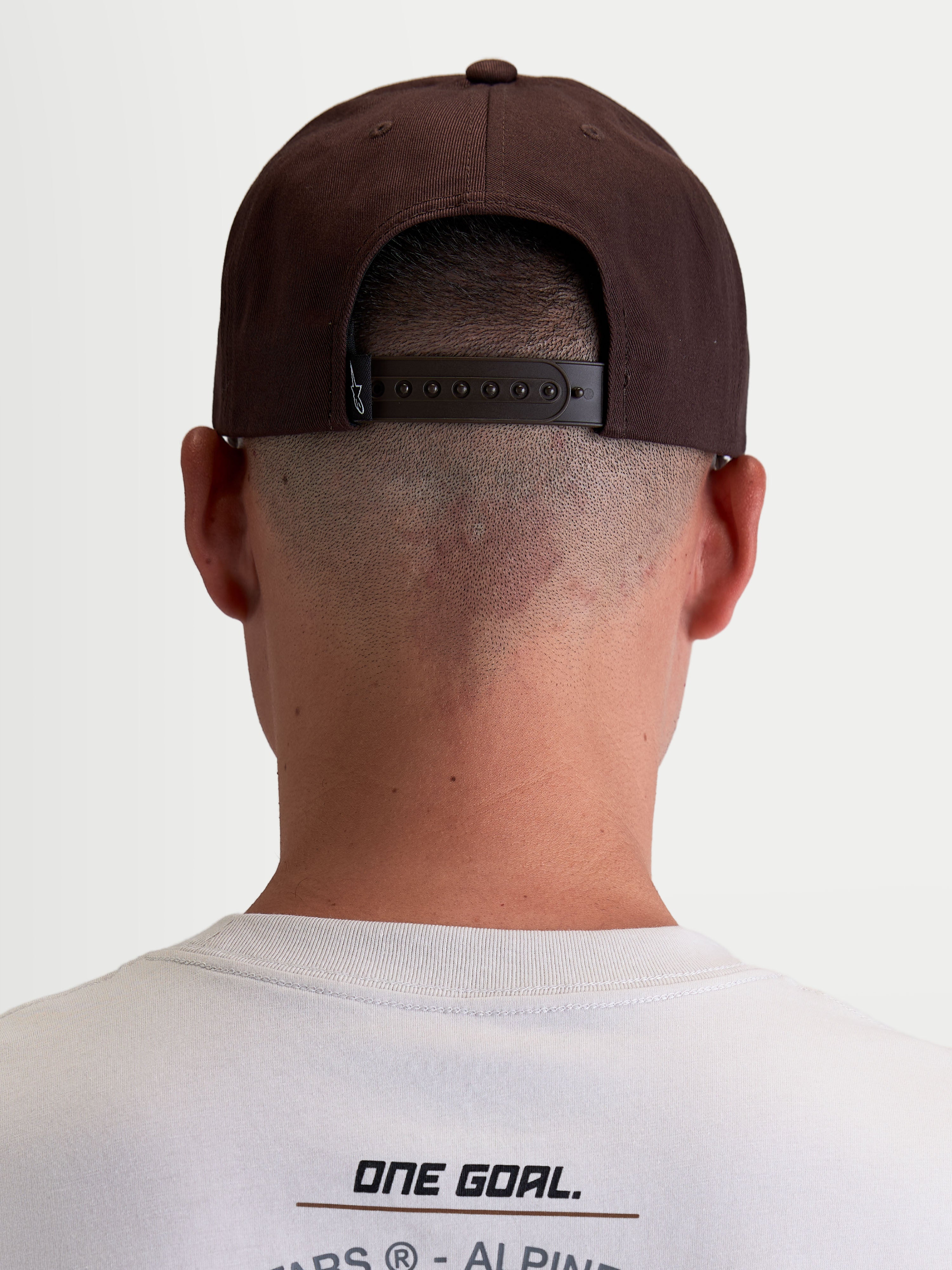 Alpinestars casquette Combo Logo Snapback, casquette de sportswear pour homme et femme, marron, vue arrière sur modèle montrant la fermeture snapback réglable et l'étiquette de marque, style motorsport décontracté.